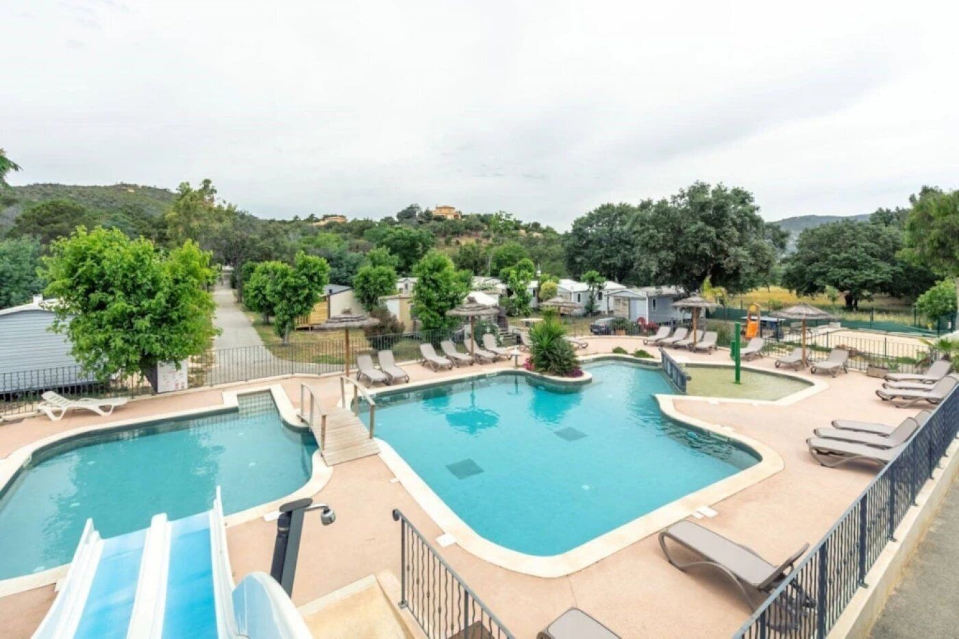 A pool area with two pools, lounge chairs, and a slide.