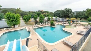A pool area with two pools, lounge chairs, and a slide.