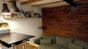 A compact living space with a dining table, a sofa, and a wooden ceiling.