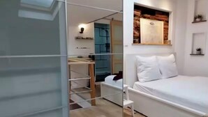 A modern bedroom with a large mirror, a bed, a wardrobe, and a skylight.