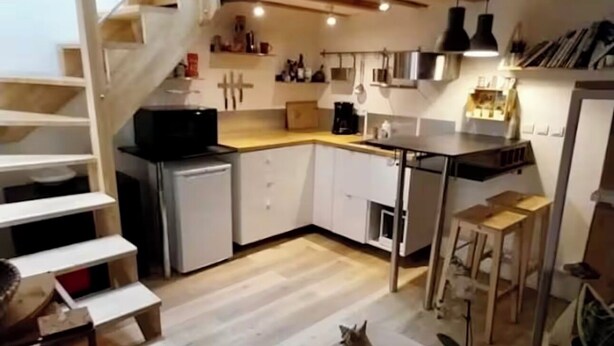 A modern kitchen with wooden beams, white cabinets, and a built-in stove.