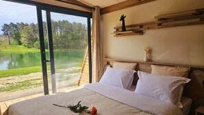 Un dormitorio con una cama grande, vistas a un lago y un cabecero de madera.