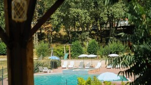 Zona junto a la piscina con mesa y sillas, un pérgola y vistas a una piscina.