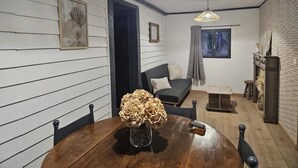 Ein gemütlicher Raum mit einem Holzespeisetisch, einem dunklen Sofa und einem Kamin.