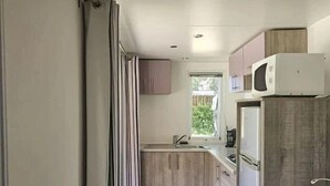 Eine kleine Küche mit Holzausstattung, einer eingebauten Mikrowelle und einem Fenster für natürliches Licht.