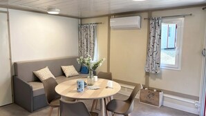 Ett mysigt rum med ett runt träbord, en grå soffa och en vas med blommor.