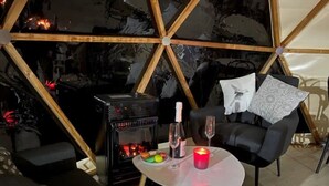A cozy room with a modern fireplace, a dining table with a candle, and a comfortable seating area. - ZEcamping piscine chiens acceptés jacuzzi locatif BBQ 30m2 4 pers (Saint-Constant-Fournoulès)