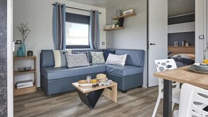 A compact living space with a sofa, a coffee table, and a dining area. - ZEcamping 4* familial 500m plage piscine couverte mobil-home TV LV BBQ (Morsalines)