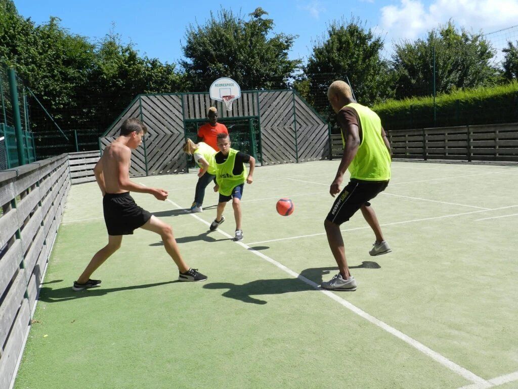 A basketball court with players in action, a basketball hoop, and a fence.