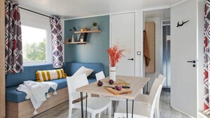 Una sala de estar moderna con un sofá azul, sillas blancas, una mesa de madera y una pared azul decorativa.
