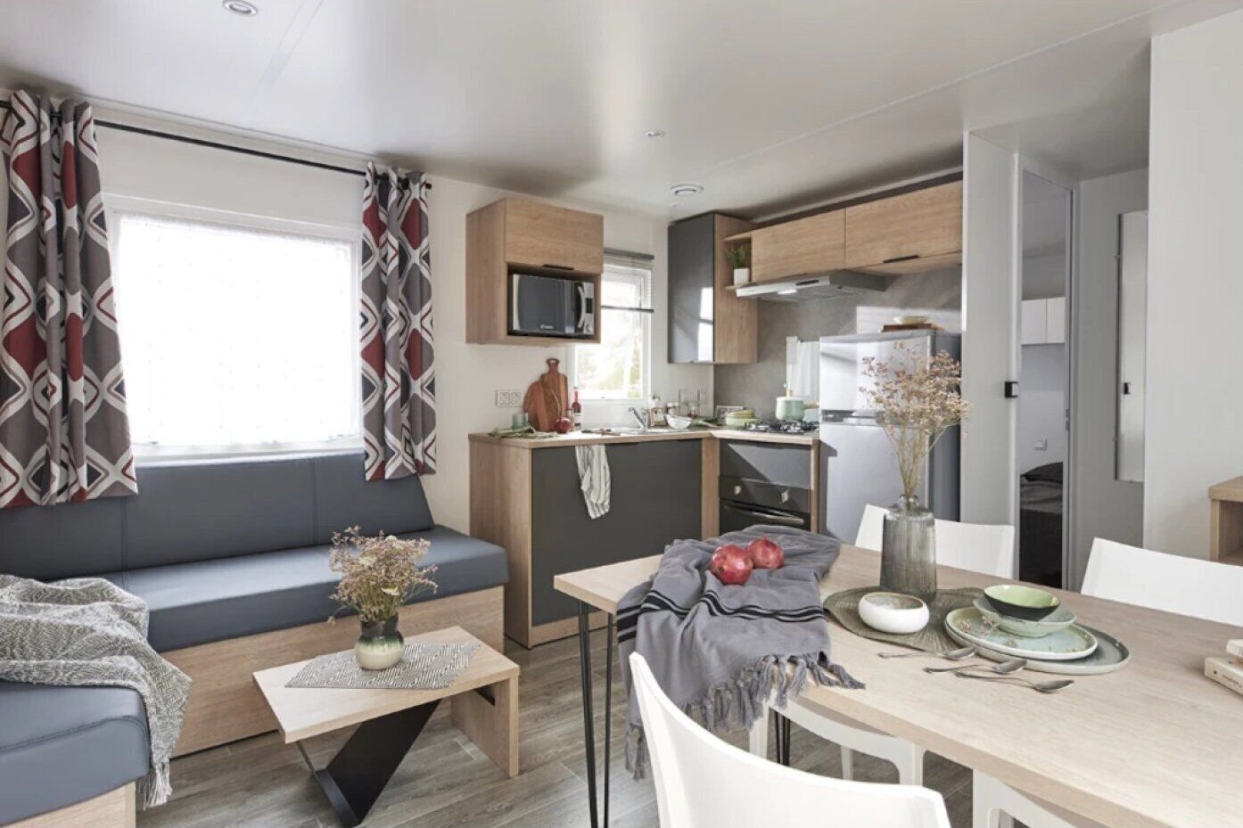 Un espace de vie compact comprenant un coin cuisine, un coin repas et un espace détente avec un canapé et une table.
