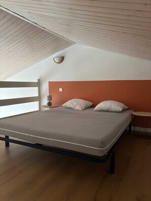 A bedroom with a bed, a nightstand, a lamp, and a wall-mounted light fixture. - ZEcamping 4* piscine couverte club enfant locatif TV 35m2 5 pers (Saint-Hilaire-de-Riez)