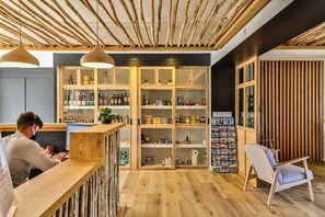 Relax in a contemporary space with a bar area and seating for one, surrounded by wooden shelves and a light-colored floor.