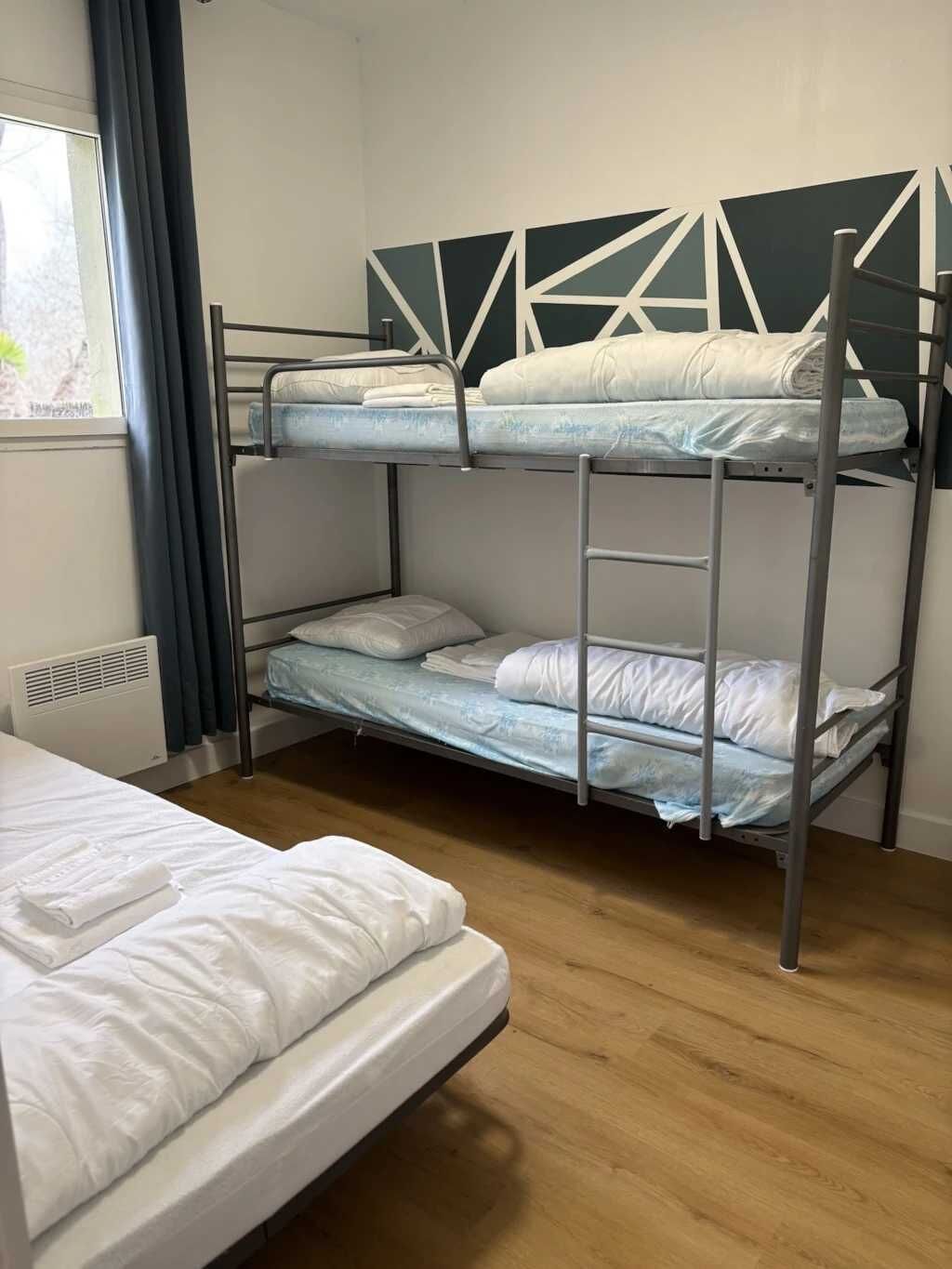 A bunk bed room with a single bed and a window with curtains.