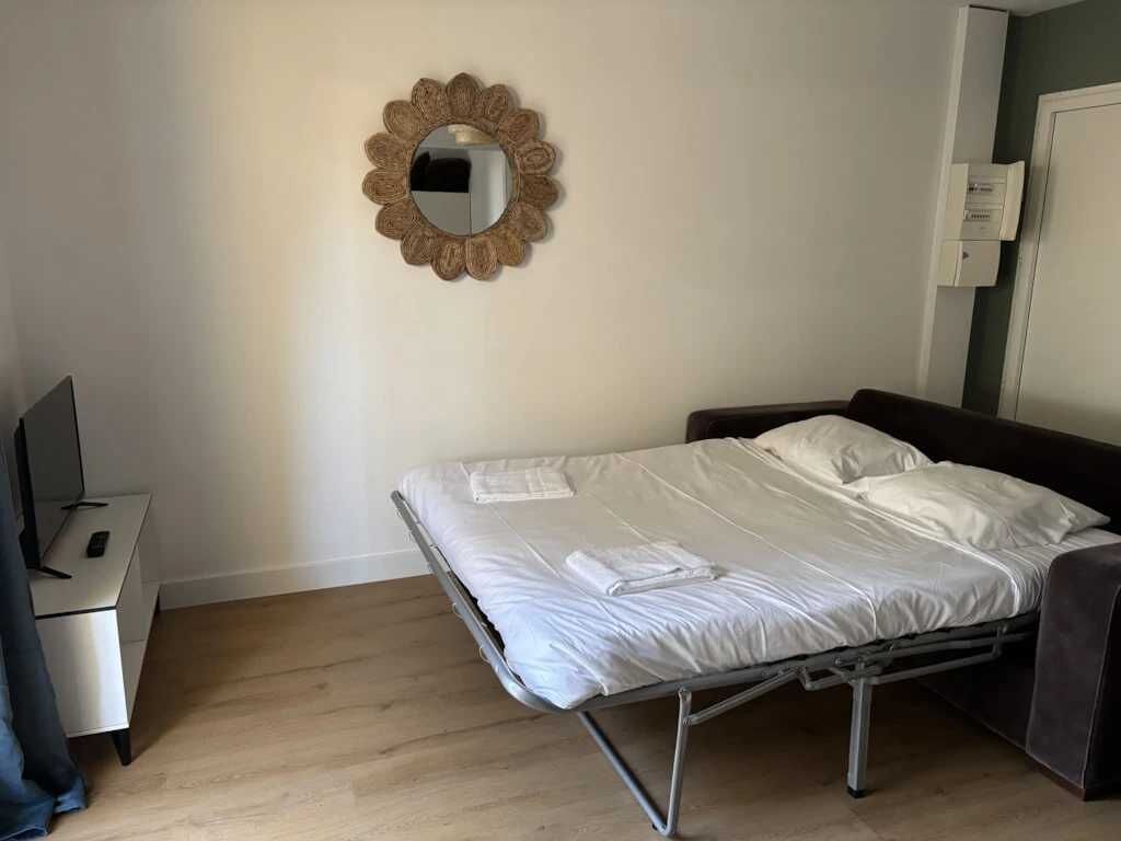 A bedroom with a metal bed frame, a small bedside table, and a mirror on the wall.