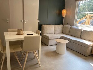 Een moderne woonkamer met een witte tafel, een beige bank en een ronde salontafel.