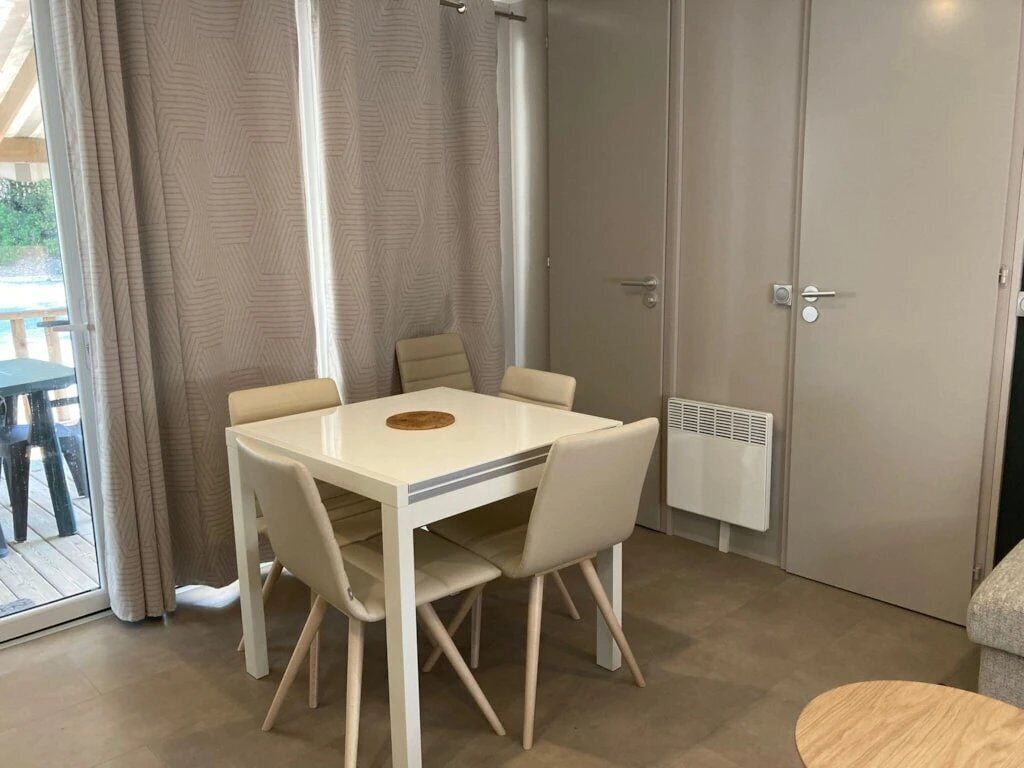 A dining area with a white table and chairs, a radiator, and a door.