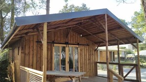 Eine Holzhütte mit überdachter Veranda, einem Picknicktisch und einer kleinen Terrassenfläche.