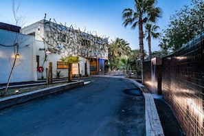 Une vue de rue avec un bâtiment moderne, des palmiers et un mur de briques.