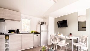 Una cocina moderna con armarios blancos, horno empotrado y zona de comedor con mesa y sillas.