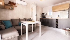 A modern living room with a sofa, a small white table, and a kitchen area with wooden cabinets and a microwave.