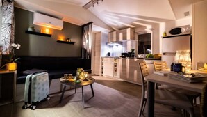 A modern living room with a sofa, a dining table, and a kitchen area in the background.