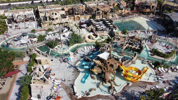An aerial view of a water park with various slides and pools, surrounded by buildings.
