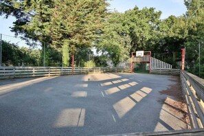 Surrounded by trees, this outdoor area offers a peaceful retreat with a paved surface and secure entry through a metal gate.