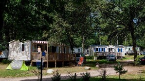Ein Campingplatz mit Mobilheimen, einer überdachten Terrasse und einem Zelt.