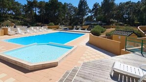 En rektangulär swimmingpool med en kakelbeklädd yta runt om, solstolar och ett område med trädeck.