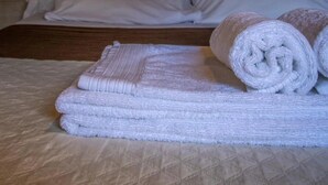 A neatly made bed with white linens and rolled towels, a wooden wall with a sign that reads 'life is beautiful,' and a simple, clean room layout. - Cabane 4 étoiles - Piscine  - ccabhid (Azur)