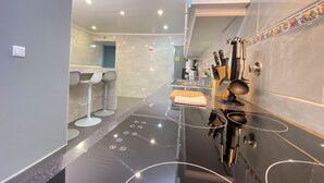 A modern kitchen with a black countertop, stainless steel appliances, and a tiled backsplash. - Sea Breeze (São Roque)