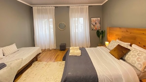 A bedroom with a bed, a smaller bed, a round mirror, and a nightstand with a lamp. - Sea Breeze (São Roque)