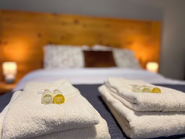 A neatly made bed with white linens and two bottles of lotion on the side. - Sea breeze (São Roque)
