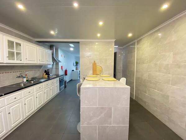 A modern kitchen with white cabinets, a central island, and a grey tiled backsplash.