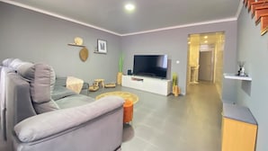 A modern living room with a grey sofa, a flat-screen TV, and a small coffee table. - Sea Breeze (São Roque)