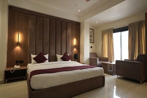Una habitación de hotel moderna con una cama grande, dos lámparas de noche, una mesita de noche, un escritorio y una silla.