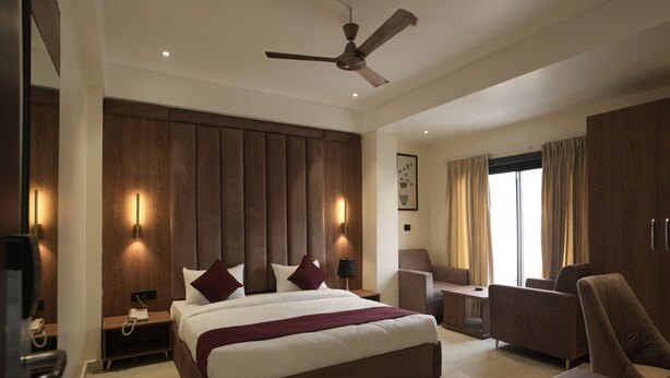 Une chambre d’hôtel moderne équipée d’un grand lit, d’un bureau, d’une chaise et d’un ventilateur de plafond.