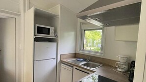 A compact kitchen with a microwave, refrigerator, dishwasher, and a coffee maker. - ZEcamping 4 étoiles piscine couverte mobil-home TV LV BBQ 33m2 (Apremont)