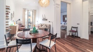A spacious living area with a round wooden table, a sofa, and a dining area with chairs.