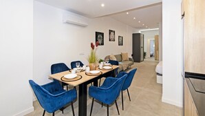 A modern dining area with a wooden table, blue chairs, and a sofa.