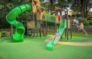 A playground with a green slide and climbing structures.
