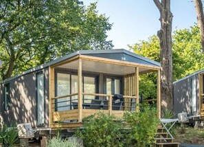 A modern cabin with a covered porch, large windows, and a visible number 'E06' on the side.