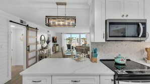 Una cocina moderna con armarios blancos, una isla grande, un microondas y una estufa.