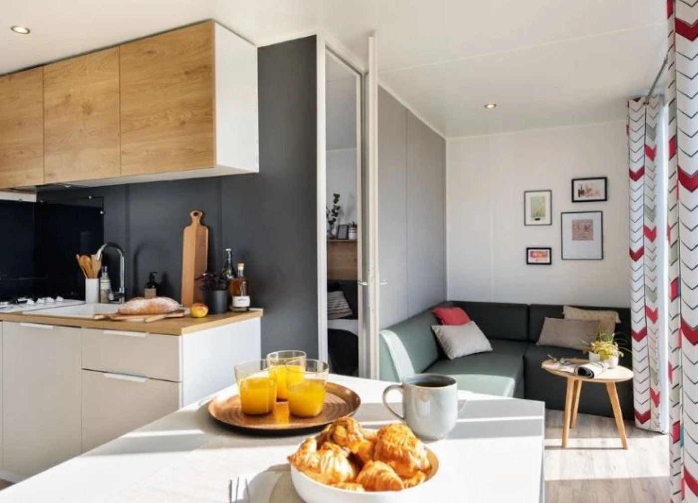 A modern kitchen with a dining area, a sofa, and a small table with a cup and saucer.