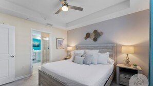 A bedroom with a large bed, a ceiling fan, a wall art piece, and a nightstand with a lamp. - 3120-105 Resort Pool View Disney Universal Orlando (Kissimmee)