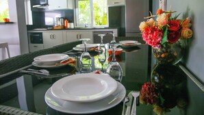 Une table à manger dressée avec des assiettes, des verres et un vase de fleurs.