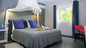 Une chambre à coucher avec un lit, une table de chevet, une chaise, une fenêtre et un rideau.