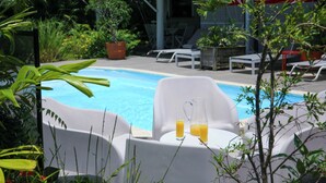Un espace aménagé au bord de la piscine, avec des chaises longues et une table où sont servis des boissons.