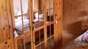 Une pièce en bois avec un lit, une table de chevet et une fenêtre.